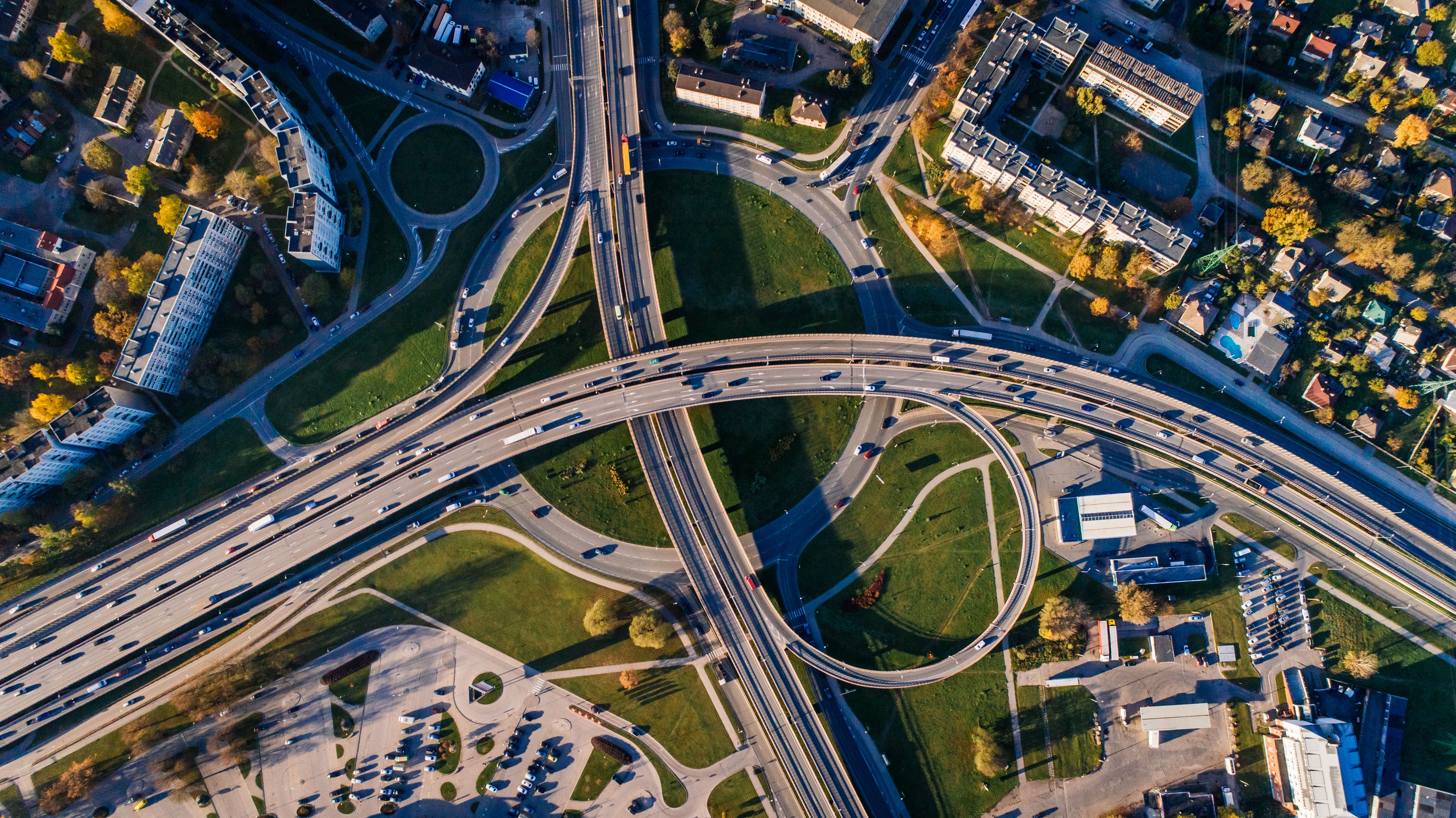 Illustrative stock photograph: Aerial view of a highway interchange, buildings, vehicles and green spaces.