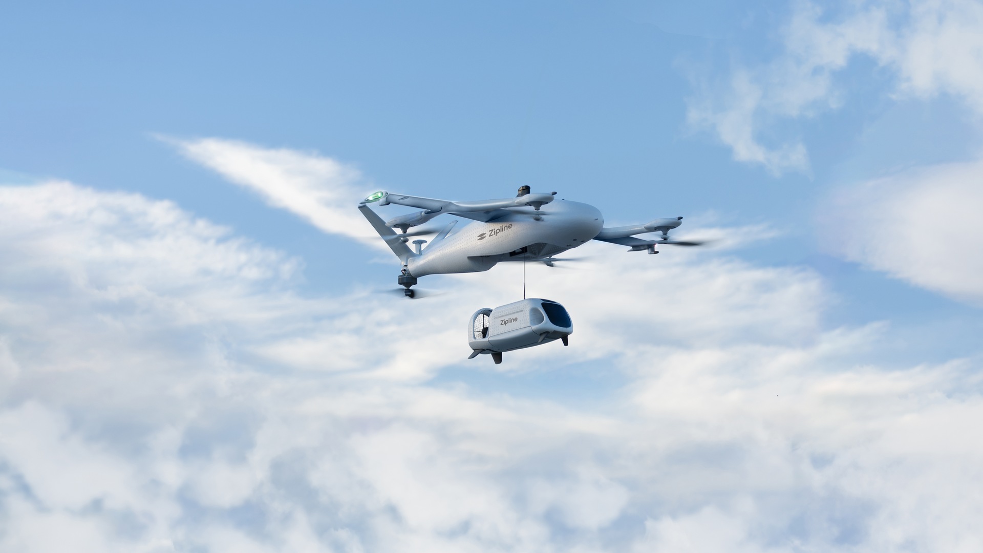 Zipline precision-delivery aircraft with its tethered delivery droid against a blue sky